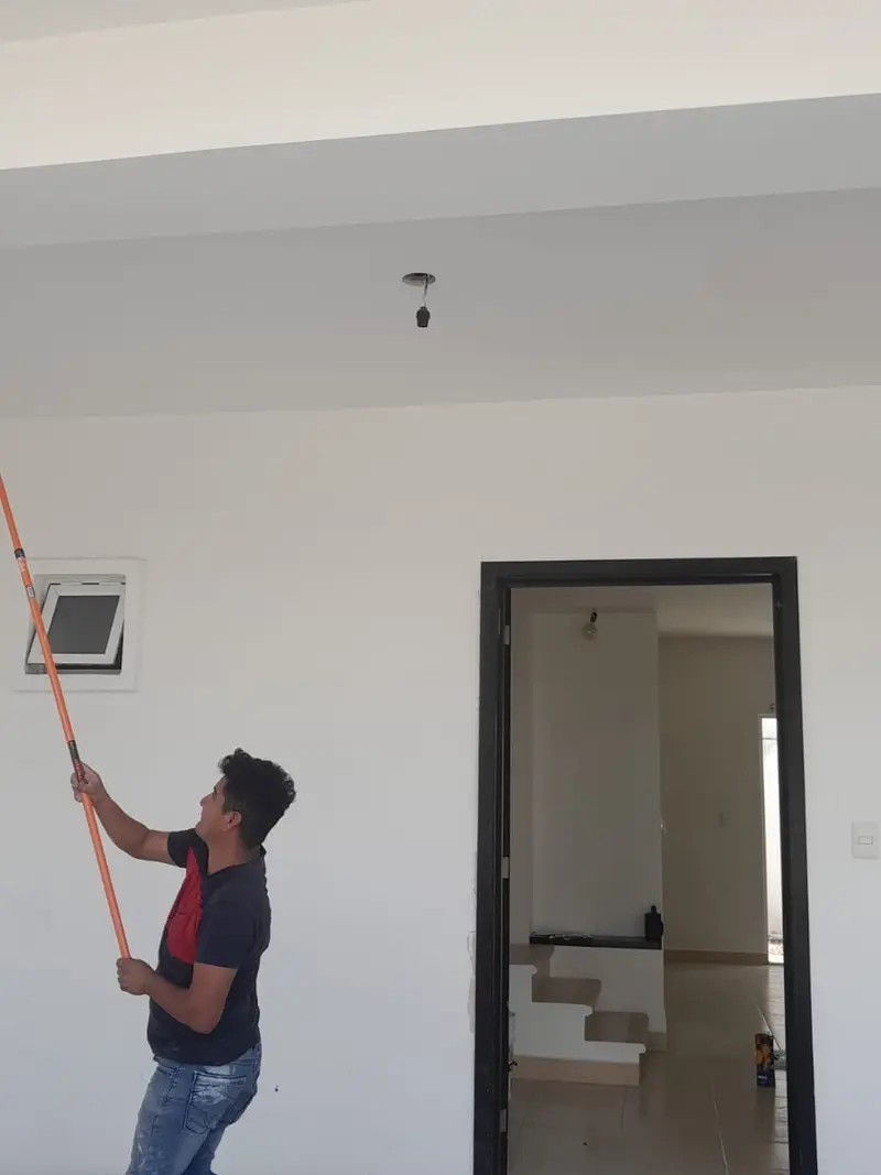 Pintor aplicando pintura blanca en el techo de una casa nueva en Playa del Carmen